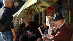 Gente mayor sentada al sol junto a un supermercado de Monforte