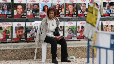 Una mujer israel, sentada delante de las fotografas de los rehenes que an quedan en manos de Hams.