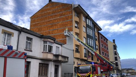 Bomberos retirando planchas que el viento ha arrancado de un edificio