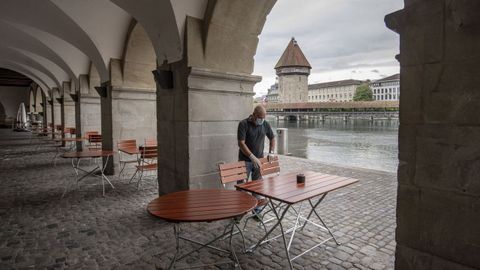 Un camarero prepara a terraza dun restaurante de Lucerna