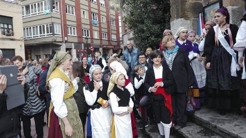 Un grupo de personas ataviadas con el traje tradiciopnal asturiano esperan a la entrada de la iglesia