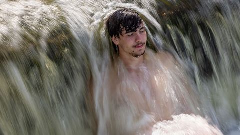 Un hombre se refresca bajo una cascada de agua en Praga.