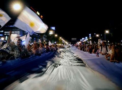 Los manifestantes sujetan una bandera argentina gigante cerca del Obelisco bonaerense.