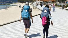 Una pareja de peregrinos pasando por la playa de Samil