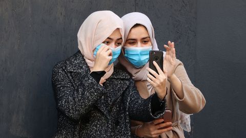 Dos mujeres, ataviadas con mascarillas, con su telfono en Londres