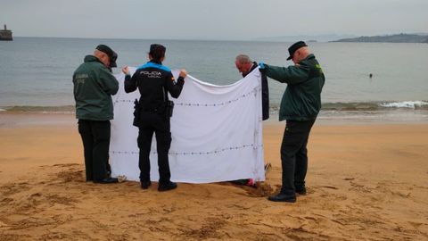 Efectivos de la Guardia Civil y de la Polic�a Local de Goz�n tapan el cuerpo en la playa de Luanco