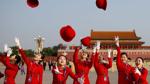 Varias azafatas lanzan sus sombreros al aire mientras posan para los fot�grafos en la plaza de Tiananmen, antes de la sesi�n de clausura del XIX Congreso Nacional del Partido Comunista de China.