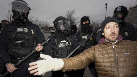 Cuatro agentes del ICE junto a un manifestante en la ciudad de Mine�polis.
