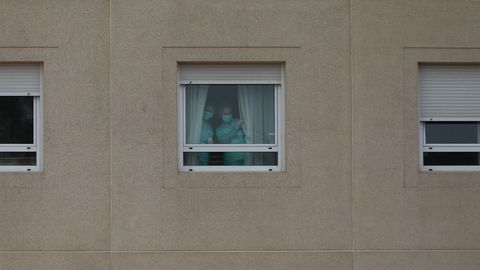 20 de marzo, d�a 6 de confinamiento. La situaci�n de residencias de mayores  de Galicia distaba mucho de las de otros puntos de Espa�a, como la de Monte Hermoso en Madrid, donde el 19 de marzo ya hab�an fallecido 17 ancianos. A�n as�, desde el primer momento tambi�n se convirtieron en foco de preocupaci�n en la comunidad. En la imagen, uno de los centros gallegos afectados, el situado en el barrio de San L�zaro, en Santiago. Dos trabajadoras saludan tras las ventanas