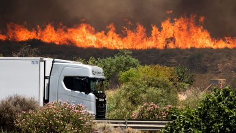 Un cami�n conduce por la autopista A7 mientras el incendio avanza en Los Gallaros
