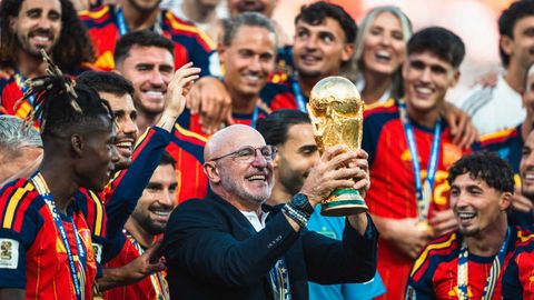 El seleccionador nacional Luis de la Fuente muestra el trofeo de campeones del mundo rodeado por sus jugadores.