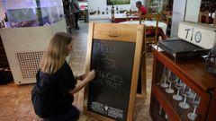La camarera del restaurante To Pepe, en Ribeira, ayer, escribiendo en la pizarra el men del da.