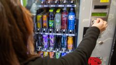 Una mujer introduce dinero en una m�quina expendedora de bebidas en Pontevedra