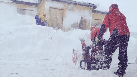 Varias personas tratan de despejar el acceso a uno de los edificios con una quitanieves el�ctrica en Fuentes de Invierno