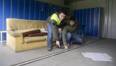 Dos trabajadores muestran la abertura que hay en la base, por donde se cuelan los ratones. 