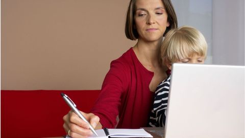 Madre trabajando con un portatil mientras cuida un ni�o