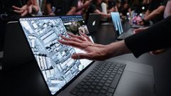 Asistentes al lanzamiento del nuevo MacBook Pro interact�an con su pantalla t�ctil.