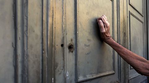 Un pensionista se apoya contra la puerta principal de una sucursal del Banco Nacional de Grecia mientras espera recibir parte de su pensi�n.