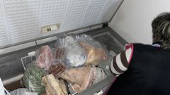 Una mujer muestra su congelador lleno de productos caseros