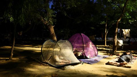 Varias personas acampan a la sombra en Nueva Dehli, en la India.