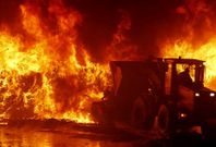 Una excavadora lucha contra las llamas en el incendio que sufri� la planta de Nosti�n.