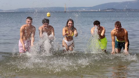 Cinco jvenes juegan con el agua en la playa A Compostela de Santiago