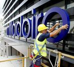 Un operario coloca el cartel de un centro comercial en O Milladoiro.