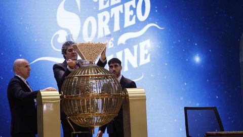 Varios responsables introducen las bolas de los premios en su correspondiente bombo durante preparativos para el sorteo de la Lotera de Navidad este domingo en el Teatro Real, en Madrid