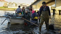 Los mariscadores, desembarcando de la lancha que los recogi� tras faenar en la r�a de O Burgo.