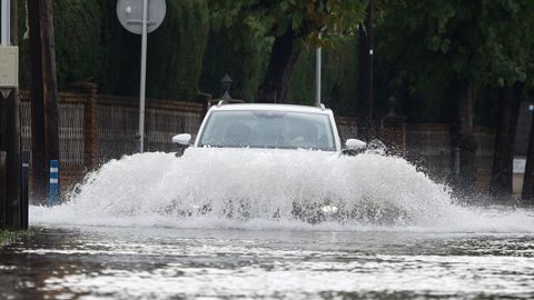 Un vehículo trata de hacerse paso por una calle inundada en Castelldefels (Barcelona)