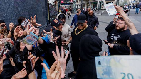  El rapero Yung Beef (c), rodeado de guardaespaldas, lanza billetes reales para promocionar su �ltimo trabajo,  en el centro de Madrid.