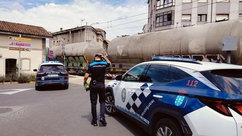 Un Policía Local, esta tarde junto al paso a nivel de A Florida, con el tren que atropelló a la víctima todavía detenido en la vía