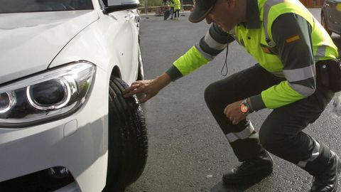 Un guardia civil examina los neumticos de un coche en una carretera de Ferrol.