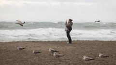 Una mujer fotograf�a este s�bado la playa de la malagueta, en alerta naranja por lluvias y fen�menos costeros