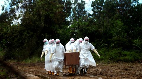 Funcionarios municipales portan un atad en un enterramiento masivo en Tarakan, Indonesia