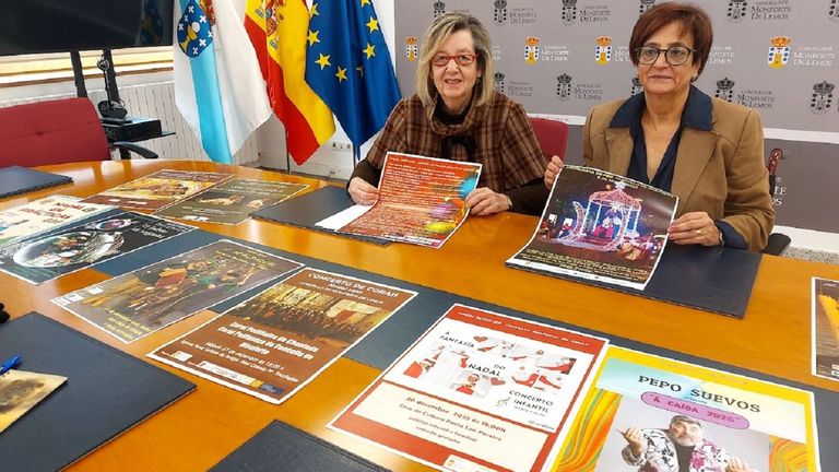Marina Doutn y Gloria Prada con carteles de las diferentes actividades del programa