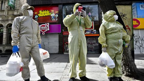 En la capital de Bolivia, La Paz, hombres enfundados en trajes de proteccin esperan en la calle tras hacer la compra