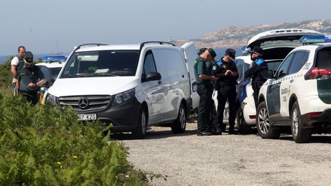 Fuerzas de seguridad y la furgoneta de la funeraria en la que fue trasladado el cuerpo del submarinista recreativo recuperado este viernes en O Carreiro, en O Grove