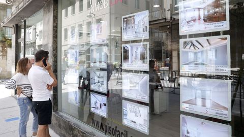 Dos personas analizan las diferentes ofertas de casas y pisos que se ofrecen en una agencia situada en la ciudad de Lugo.