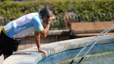 Un ciclista se refresca del calor en la fuente de la Escandalera de Oviedo