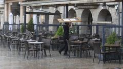 Un camarero de un bar del centro de Lugo recogiendo la terraza durante la tormenta que cay� la tarde del 24 de junio en la ciudad.