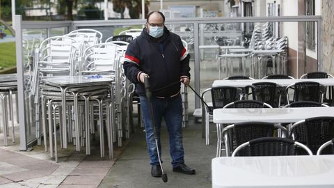 Abilio Golpe, limpiando la terraza de la Vinoteca Aquitania, que reabrirá este martes en el Parquemar de Covas