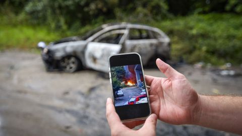 En el m�vil se puede ver la imagen del incendio que destruy� el coche del fondo en Mollavao