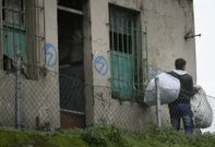 Un vendedor ilegal sale de la casa abandonada de Puerto Rico con sus petates. 