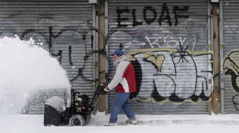Un hombre utiliza una peque�a m�quina quitanieves para despejar una acera en el barrio de Brooklyn.