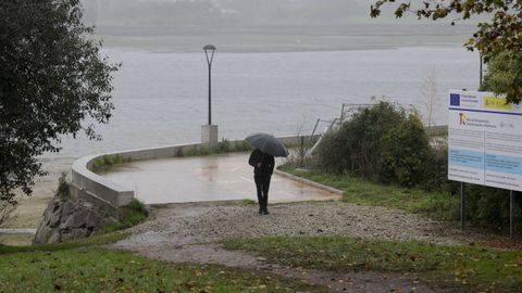 oleiros.Un vecino camina por el paseo pegado a la ra en O Graxal, Oleiros