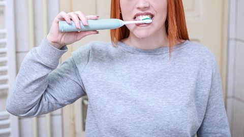 Una mujer lav�ndose los dientes.