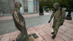  Un soldado desinfecta la estatua de Woody Allen, decorada con una mascarilla, este domingo, en Oviedo