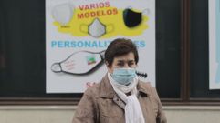 Una mujer pasa frente a un letrero que anuncia mascarillas en una calle de Monforte
