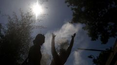 Varias personas se refrescan con los chorros de una fuente al lado del Sena